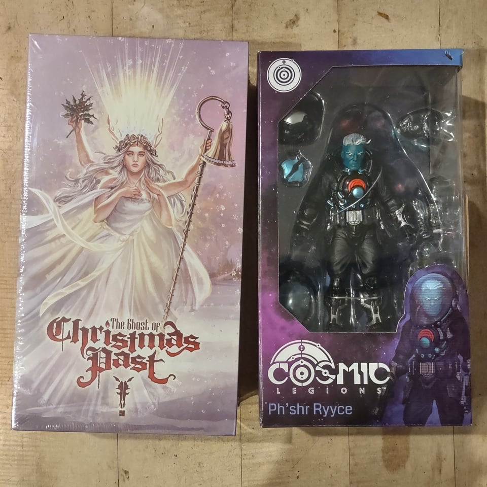Two side by side boxes for action figures. One is a white box with art of a multi-armed, spectral woman in white robes marked