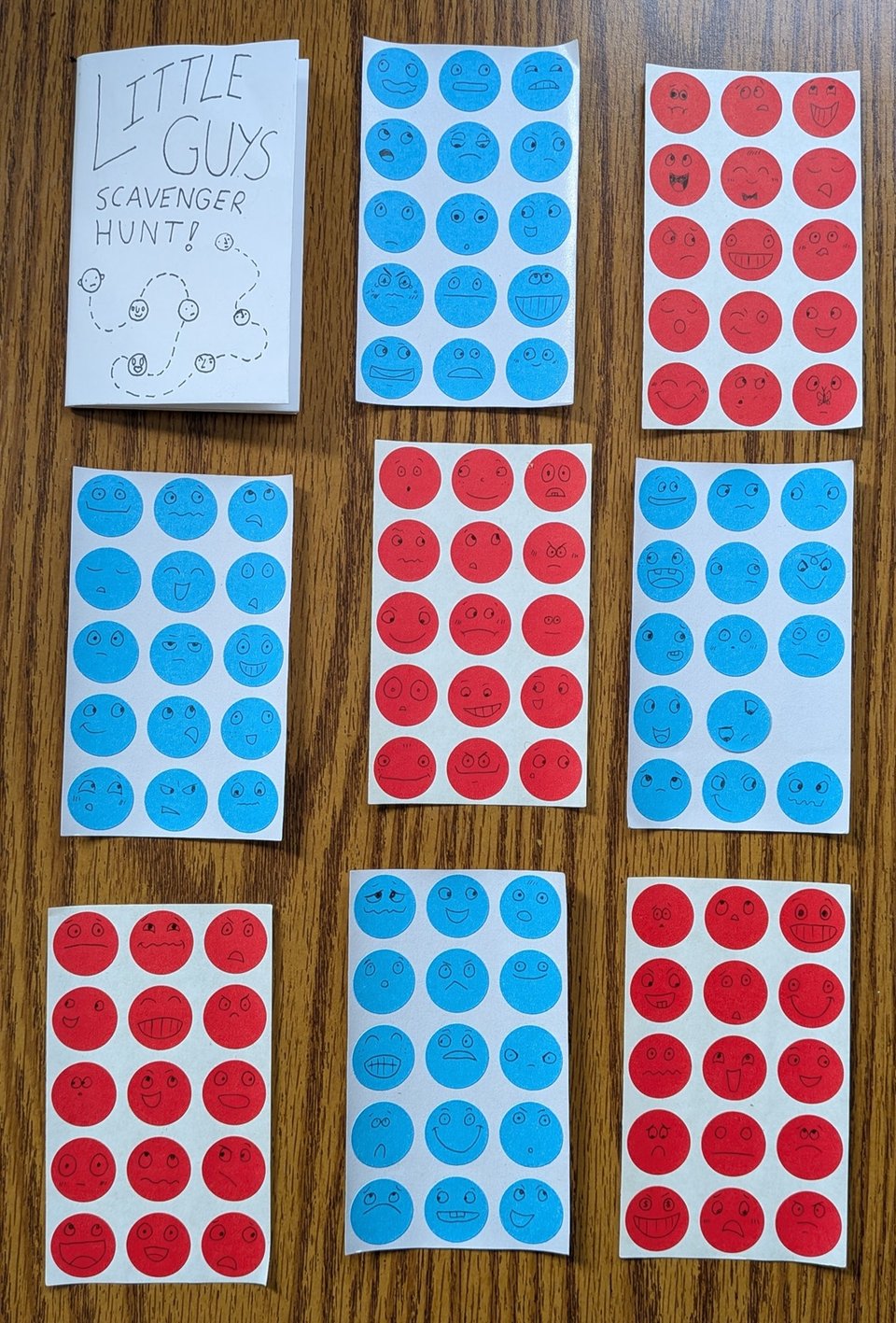 sheets of red and blue dot stickers, with faces drawn on each sticker showing a wide variety of facial expressions. In the upper left corner is the Little Guys scavenger hunt zine.