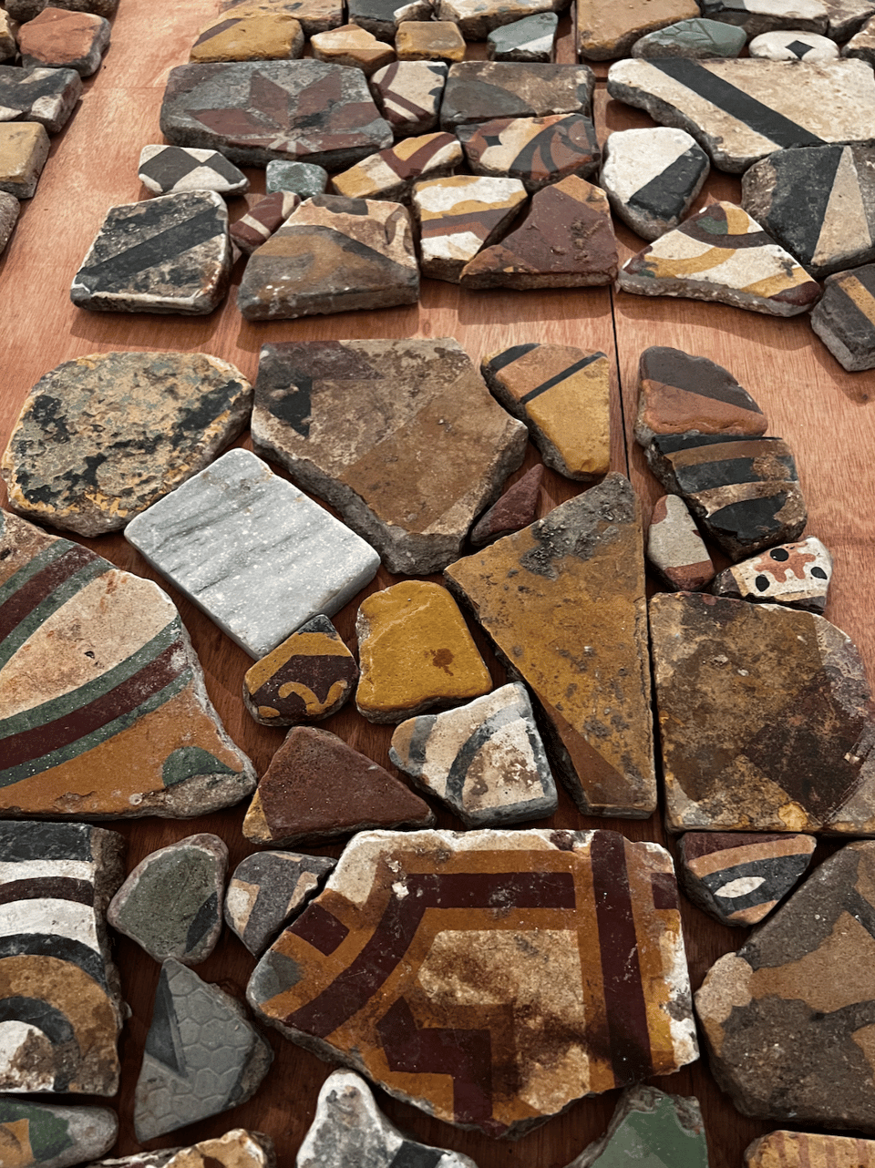 A mosaic of large colorful but worn decorative tiles arranged on a floor