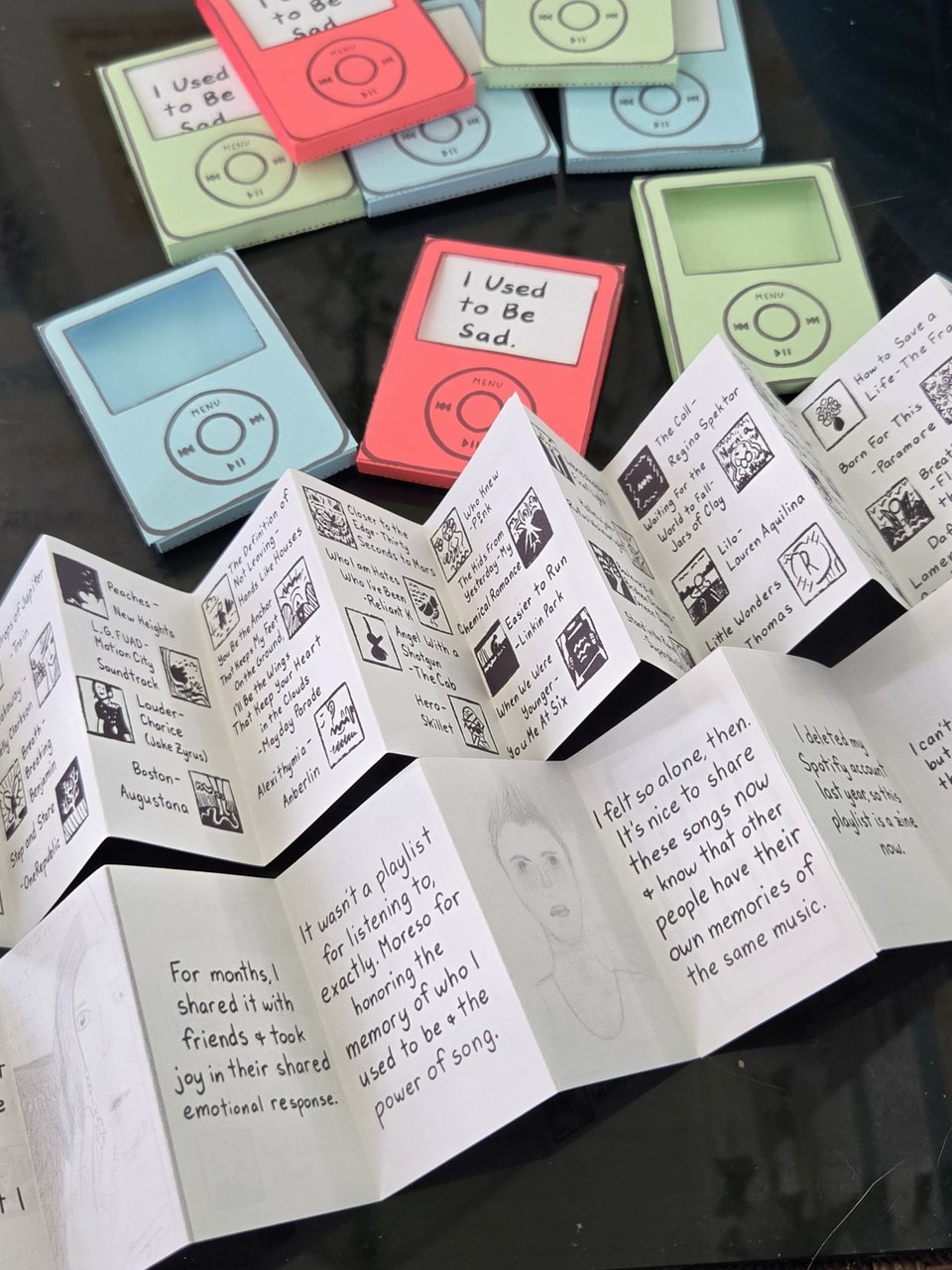 Accordian fold playlist zine with a colorful sleeve that makes it look like an ipod