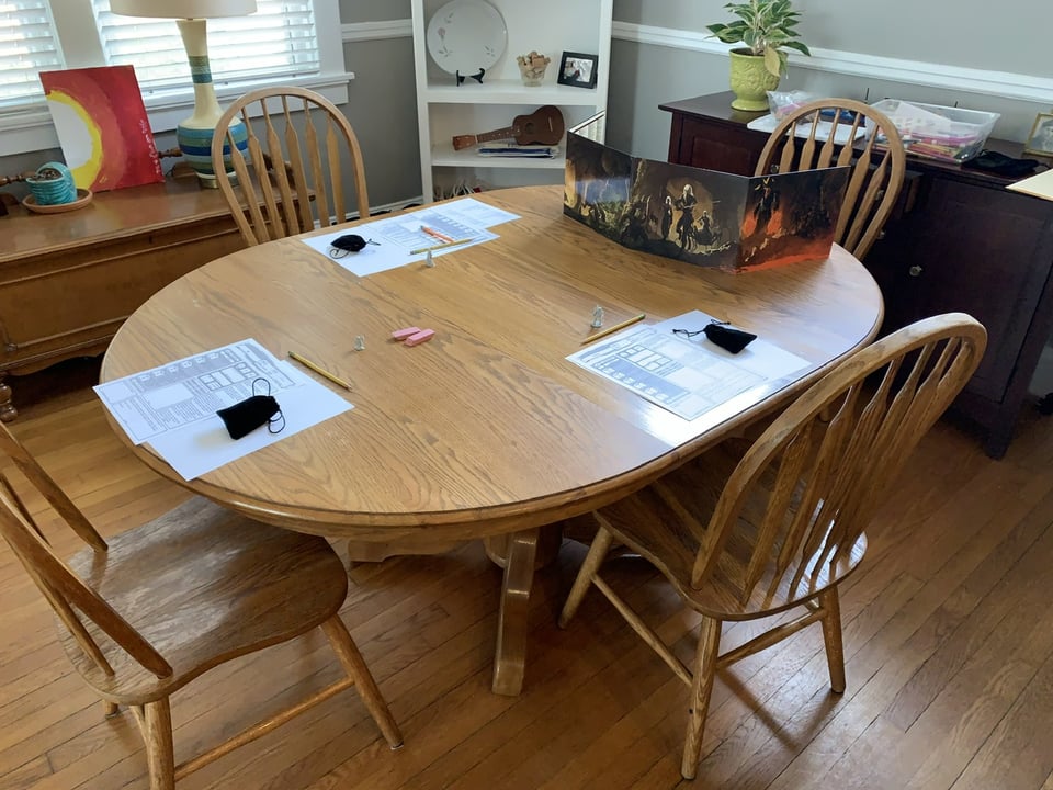 a dining room table and chairs with D&D set up for three kids