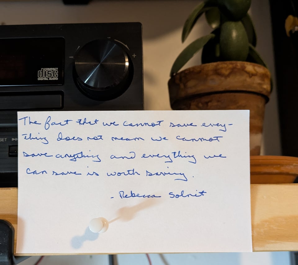 an index card, with the following handwritten on it: The fact that we cannot save everything does not mean we cannot save anything, and everything we can save is worth saving. - Rebecca Solnit