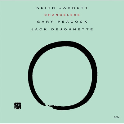 The cover for Keith Jarrett’s CHANGELESS, which is a solid light green/aqua background, and a large open black circle on it. The circle looks like it was created freehand with a thick brush; it does not quite connect all the way, leaving a small gap and evidence of brushstrokes on one end of the line that makes the circle.