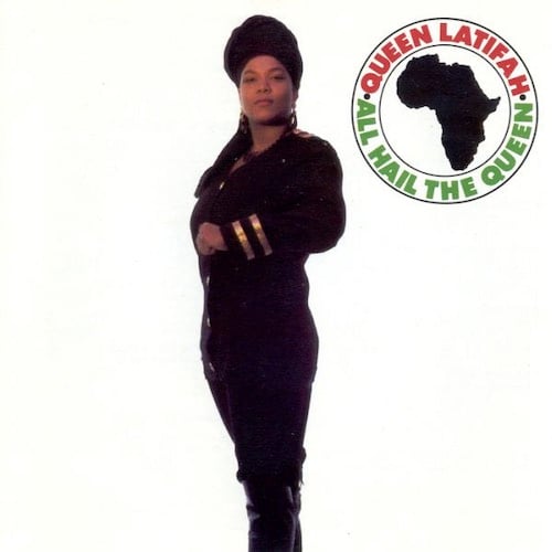 It's Queen Latifah! She's a tall, strong, proud sexy Black woman wearing a black uniform, slightly miltaristic in the Janet Jackson RHYTHM NATION way. The background is blank white.