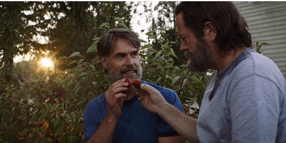 Two men share a couple of strawberries as the sun goes down.