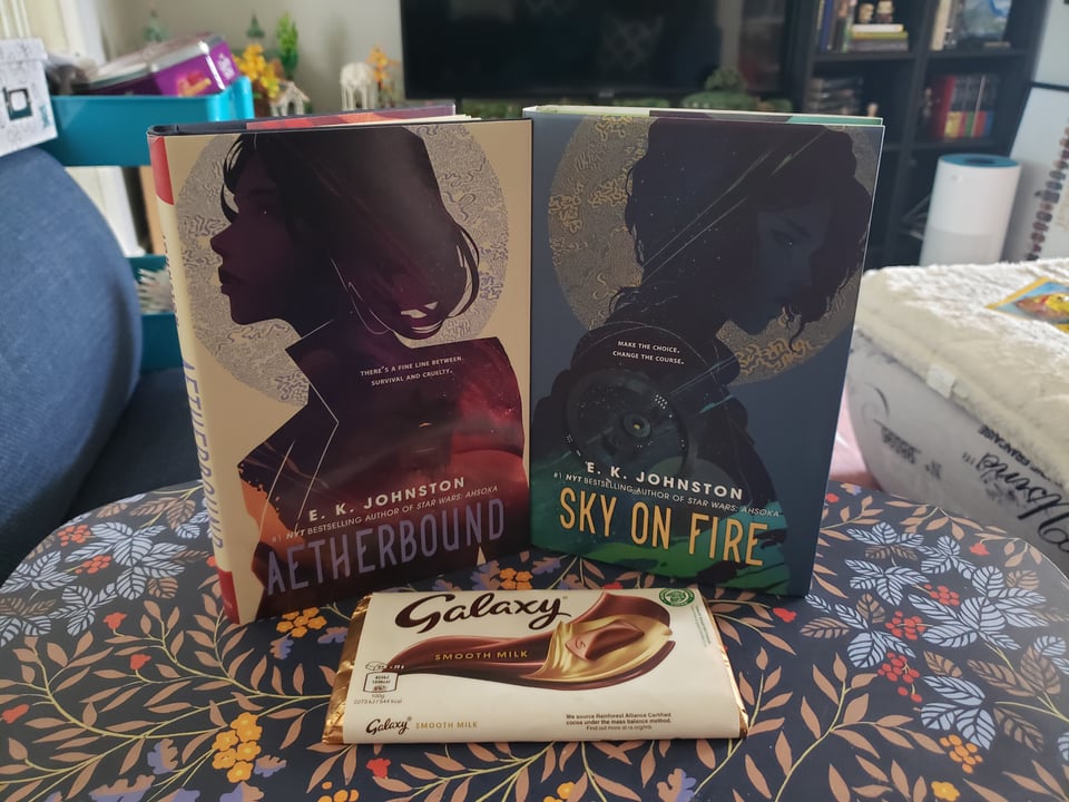a copy of Aetherbound and Sky On Fire by EK Johnston with a galaxy chocolate bar