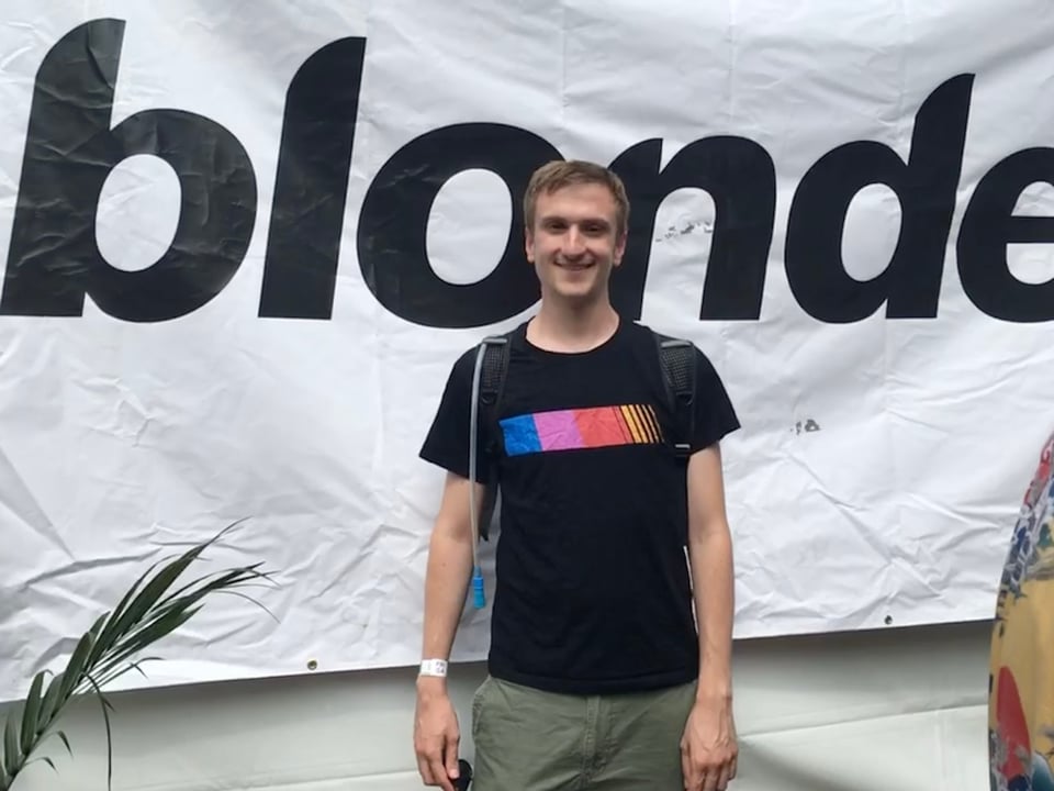 Evan poses in front of a 'blonde' banner, smiling big