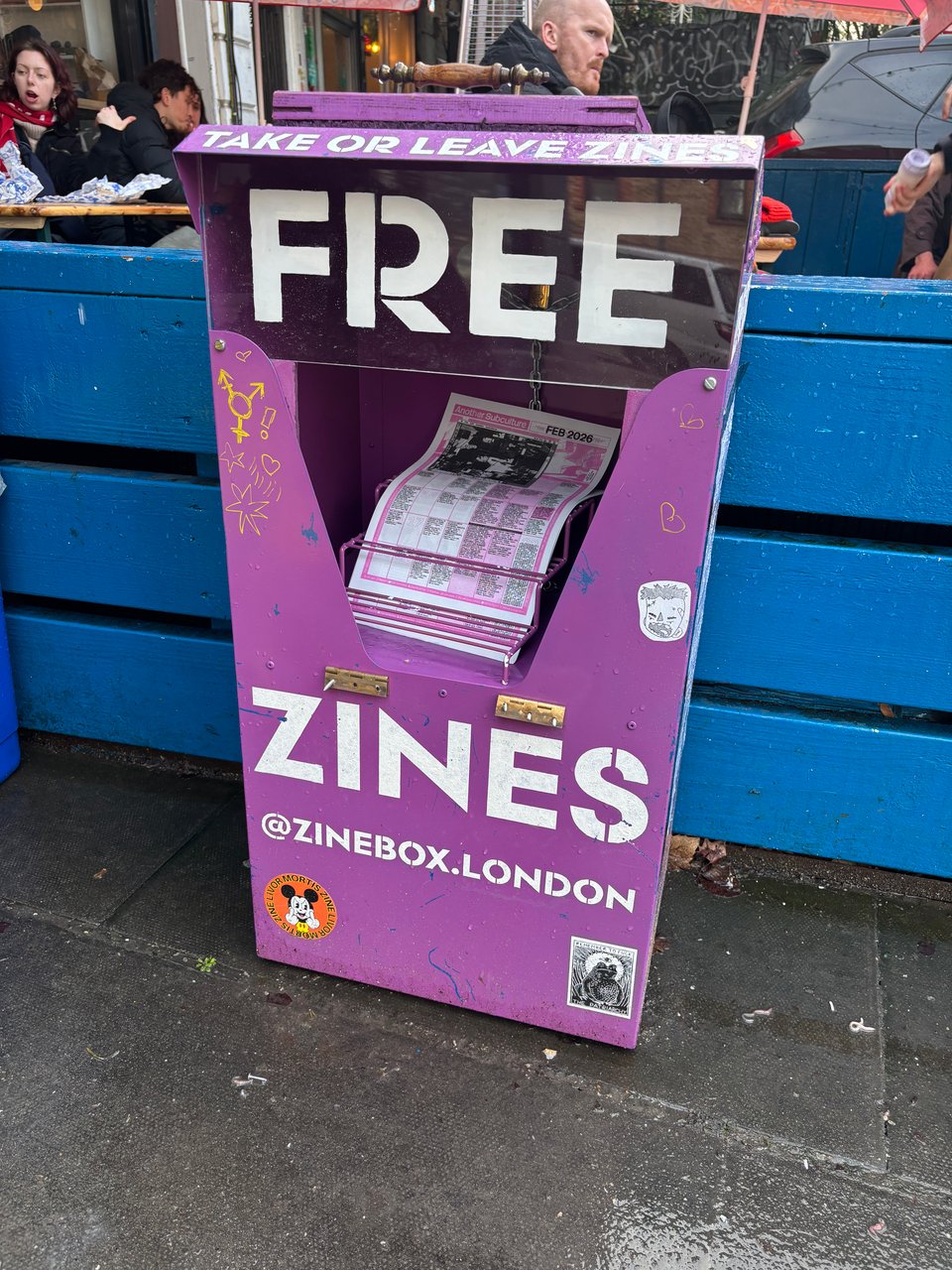 A purple newspaper kiosk, with FREE ZINES emblazoned on it, outside Toad Bakery in Camberwell.