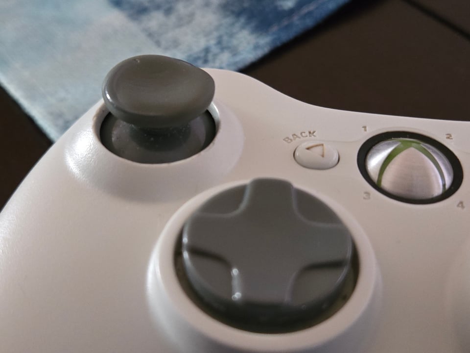 A picture of a Xbox 360 controller with a heavily used thumb stick.