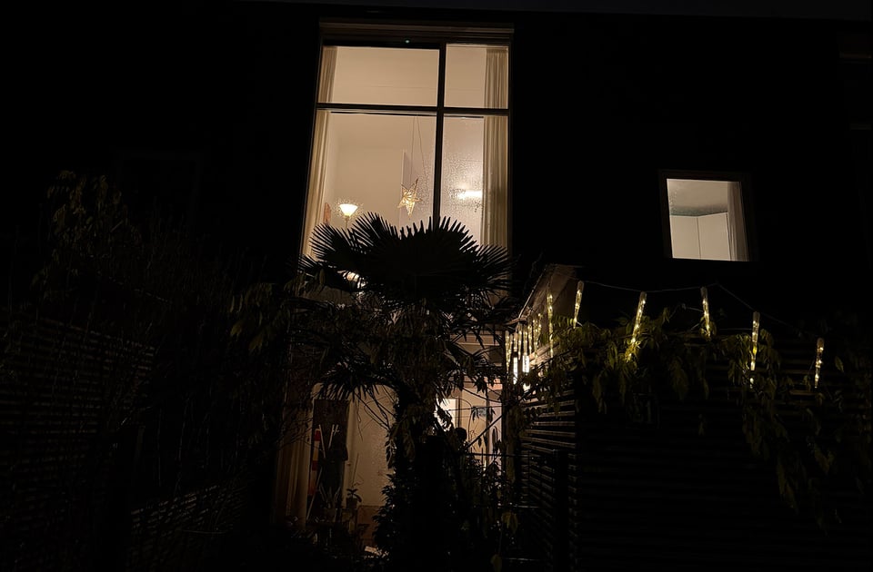 A view of large windows with the lights on and a large white star in the window for the winter light.