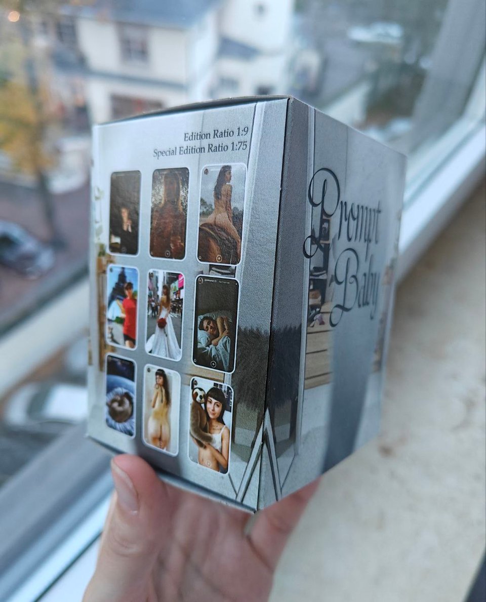 A full colour printed blindbox held up in front of a window. On one side you can see the 9 possible images that could be inside - some of them are a little blurry, but some of the clearer ones are Sarah riding a horse naked, sleeping in a dark room, holding up a sloth plushie, and totally nude with her back to the camera. It's very strange to be writing image alt-text for something called a "blindbox". If you're reading this with a screenreader I apologize