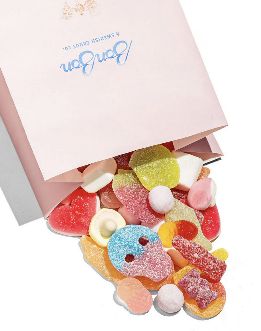 A pink paper bag of Swedish gummies in a variety of shapes, colors, and textures.