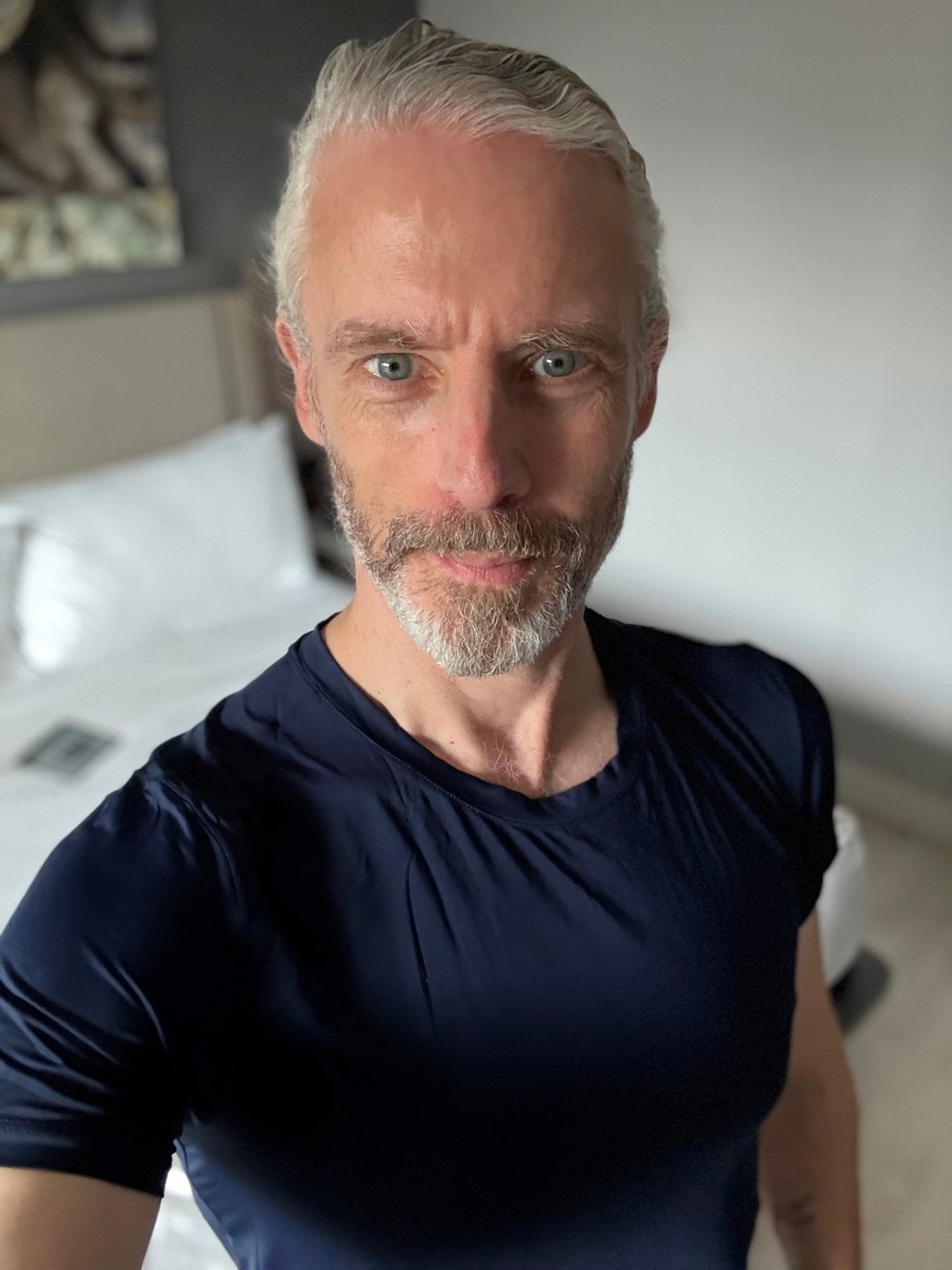 Selfie of a white man with beard in a navy T-shirt; he has long hair, but it’s slicked & tied back, so it looks like a conservative haircut, but hahaha