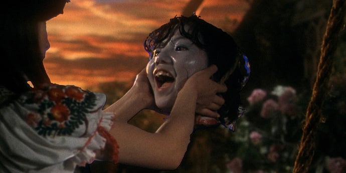 A young girl holds a still living still laughing severed head, from Hausu