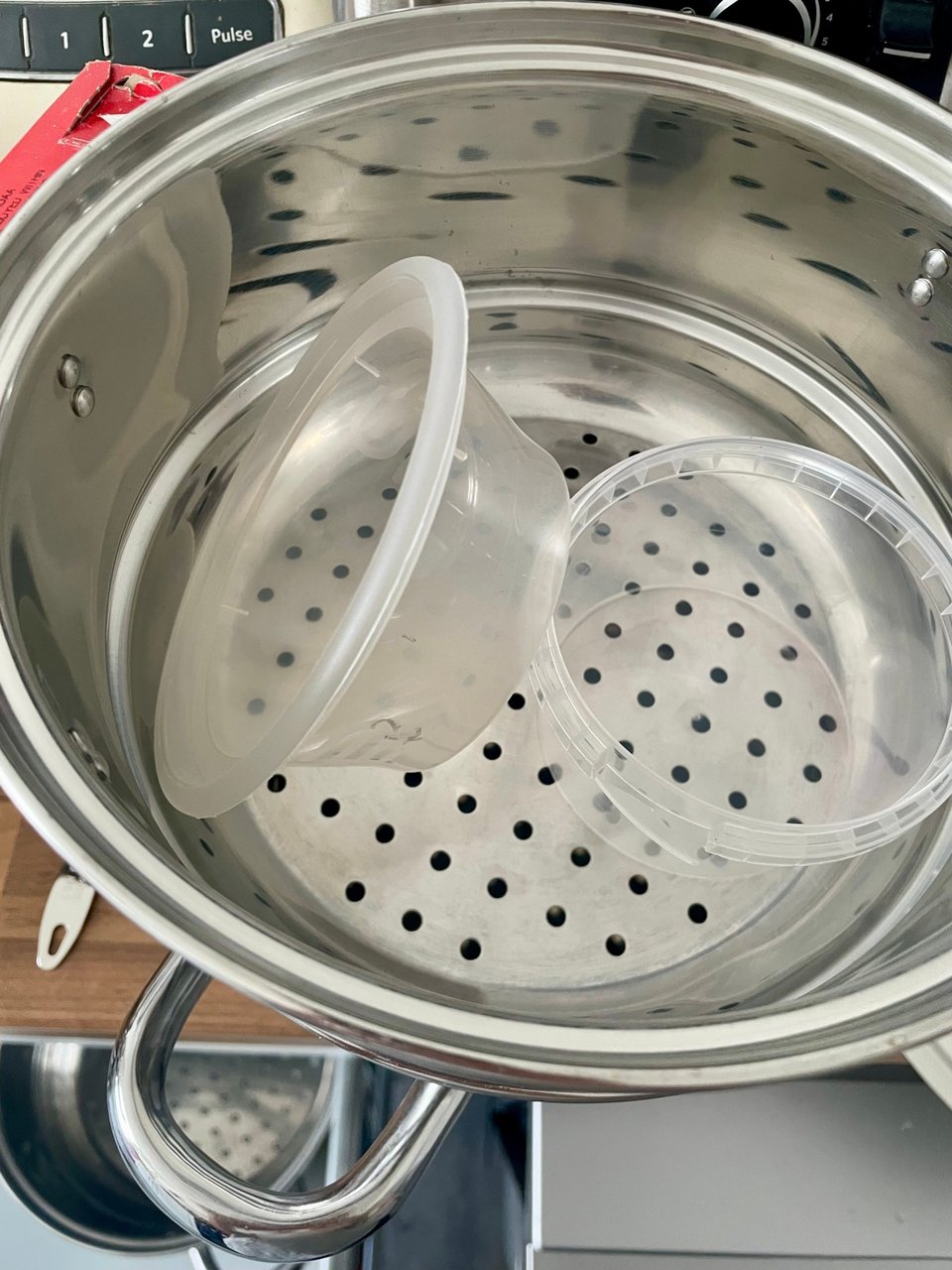 Two clear plastic tubs not quite fitting into a steamer