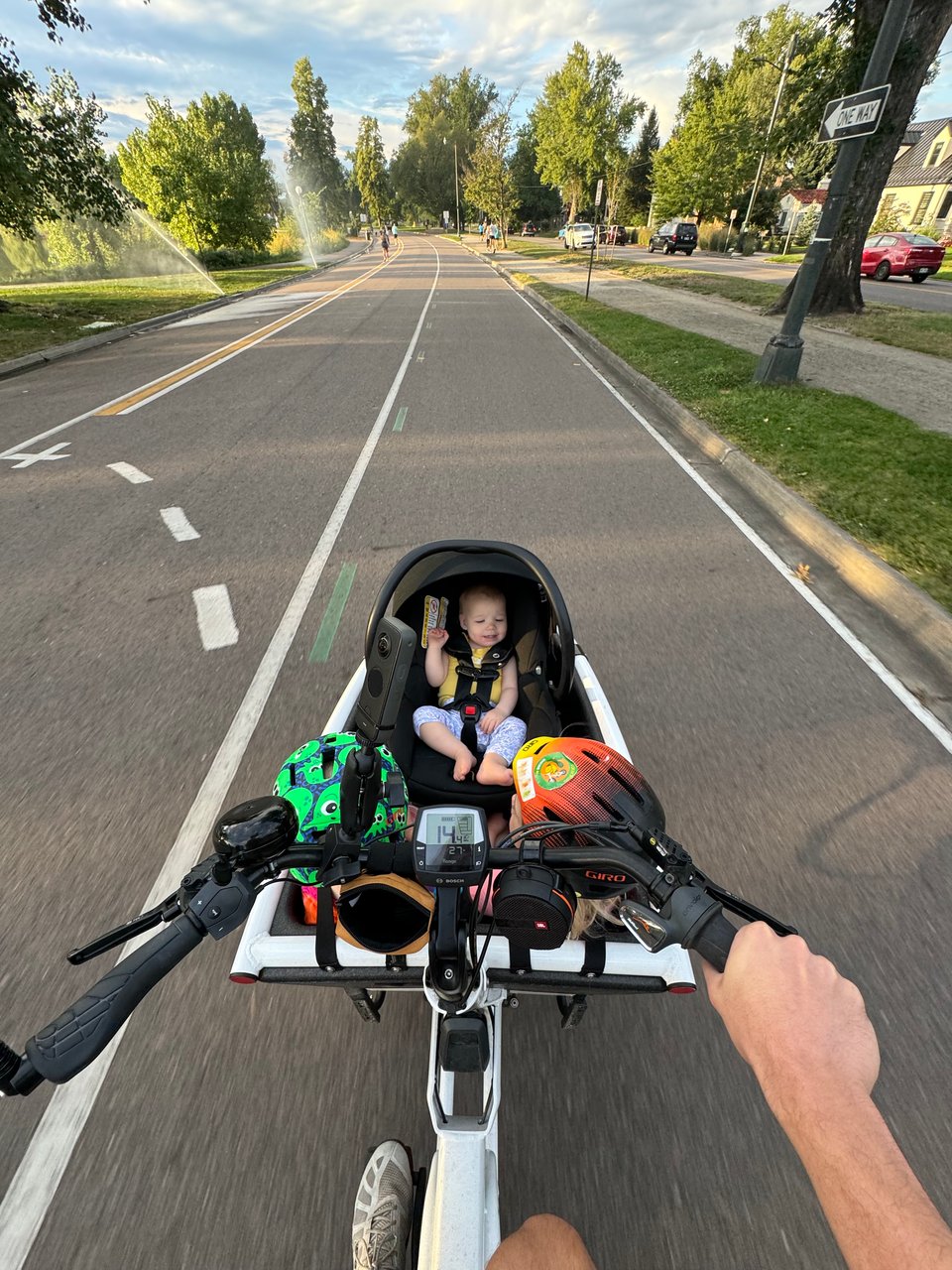 a first-person view from the rider's perspective of a bakfiets style cargo bike carrying three children