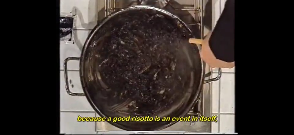 A screenshot of a Youtube video of Blixa Bargeld cooking squid ink risotto. There are subtitles that read "because a good risotto is an event in itself"