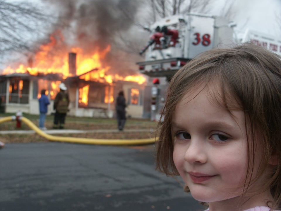 the meme of the little girl looking at the camera very sinisterly whilst a house burns in the background
