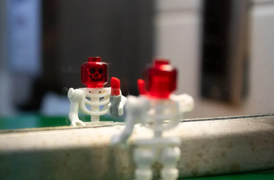 A lego skeleton looks into a mirror.