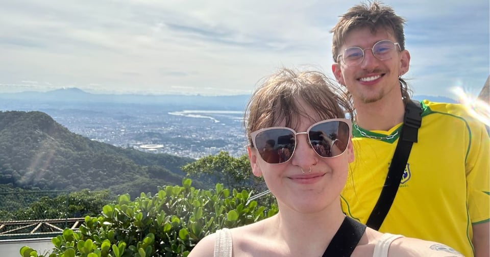 Photo shows two JMC students taking a selfie outdoors with scenery behind them during the Brazil summer study abroad program.