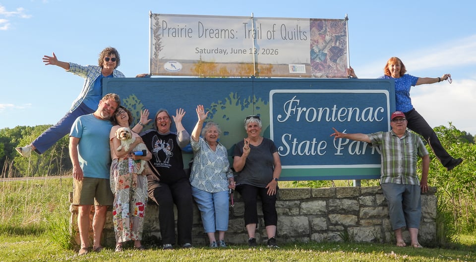 Frontenac State Park Association Arts Committee standing in front of Prairie Dreams banner and Frontenac State Park sign.