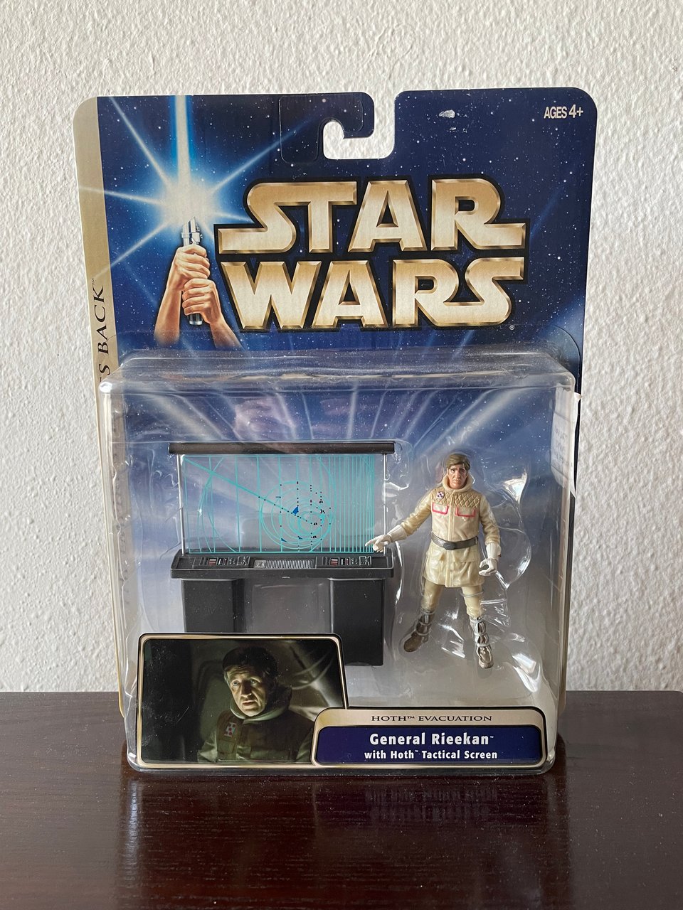 An action figure still in the package of an older stressed man pointing at a tactical screen