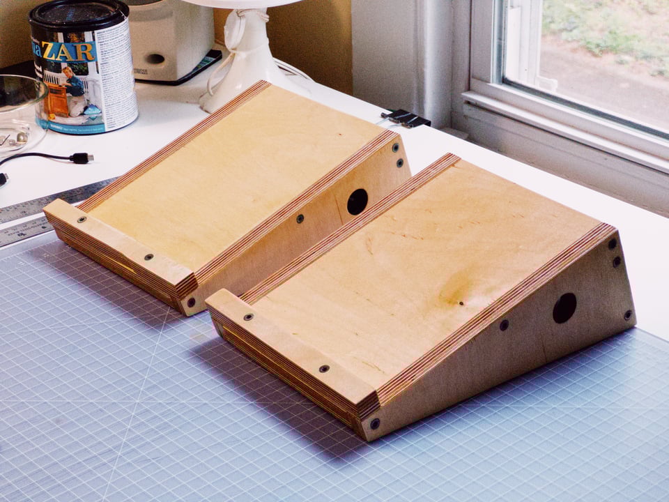 two wooden wedge-shaped speaker sands on top of a table