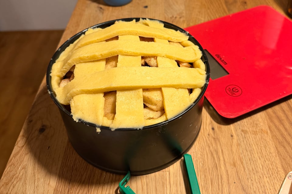 A dutch apple pie with a latticed pie crust sits on a kitchen island waiting to go into the oven.