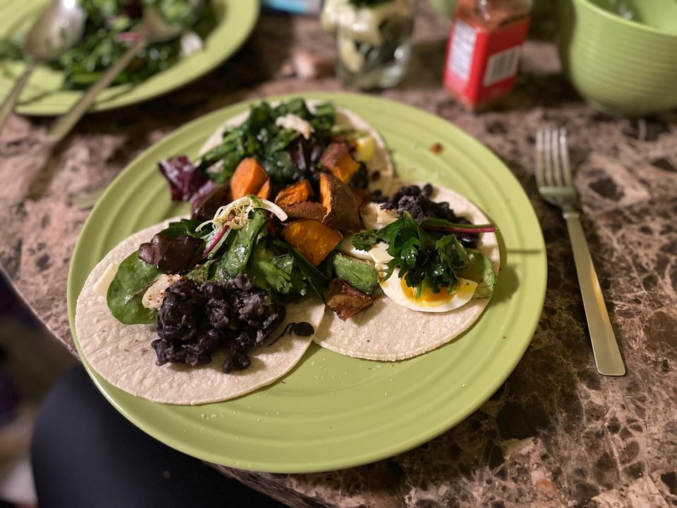 Eggs and beans and salad and sweet potato and butter nuts on tacos