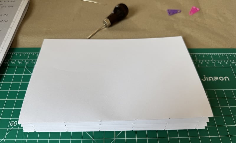 photo of some folded paper with holes in the fold, before i sewed them together in a book