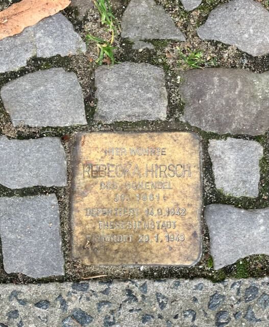 Brass plate surrounded by cobblestones engraved with a name and dates