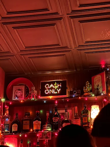 A photo of a bar with a Lite Brite that reads CA$H ONLY