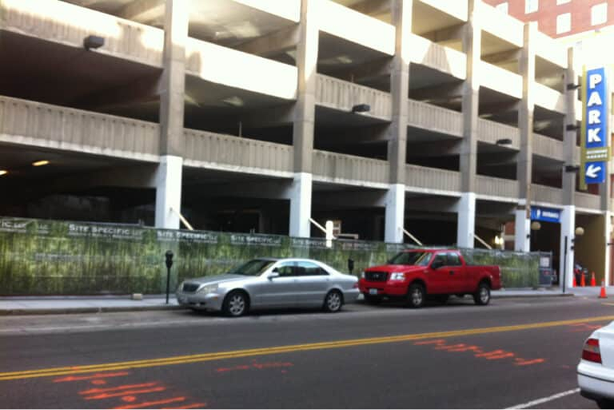 Biltmore Garage before the renovation — just a regular concrete parking garage with a lifeless fence running along the sidewalk.