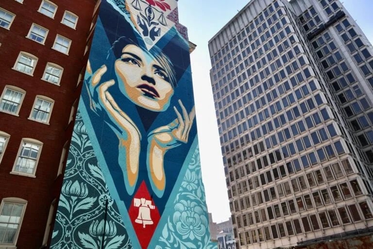 ‘Uplift Justice’by Shepard Fairey is painted on the side of a Center City office building on Arch Street, opposite the Municipal Services Building. (Emma Lee/WHYY)
