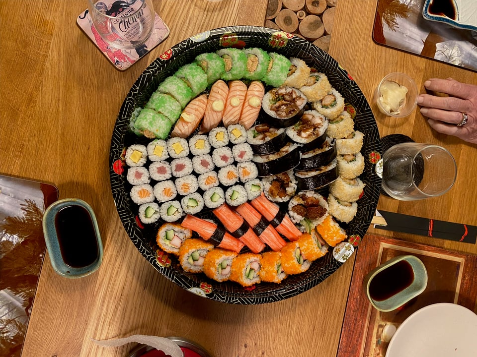 A round serving platter filled to the brim with loads of variety of sushi.