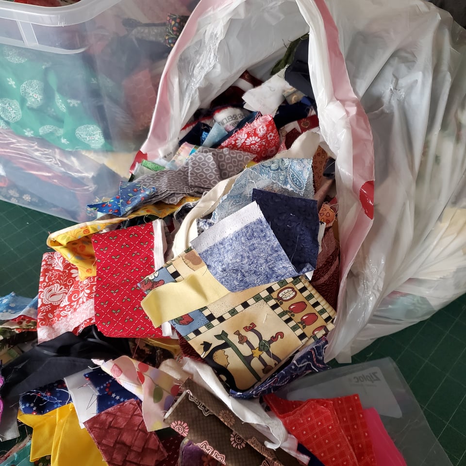 Photo of a white garbage bag with fabric scraps spilling out.