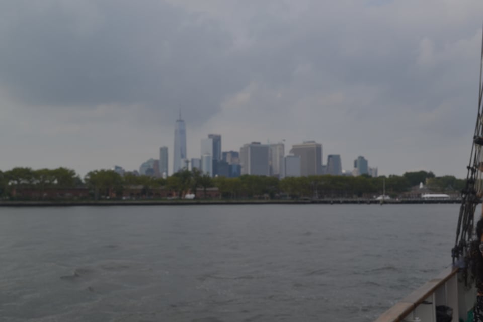 Manhattan seen from a ship in the harbor, under threatening, gray skies.