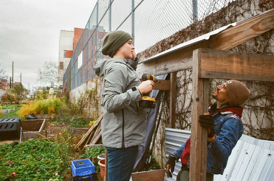 Dan and Hanna confer about how to drill screws into the metal roof of a lean to