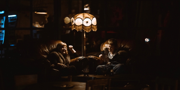 Two BLON festival guests chatting in armchairs in a cosy, dimly lit lounge — because not all conversations at BLON happen on stage.