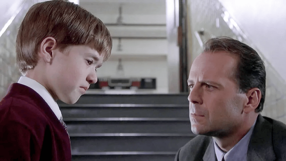 A still from the movie "The Sixth Sense", showing Bruce Willis kneeling down and looking straight on at Haley Joel Osmond