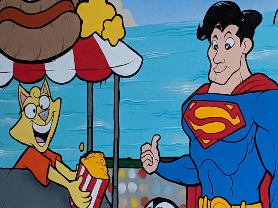 A cartoony Superman is putting his thumb up. A cartoon animal person (a cat?) is handing him a bag of popcorn from a cart with a red-and-white-striped awning and what looks like a hot dog icon