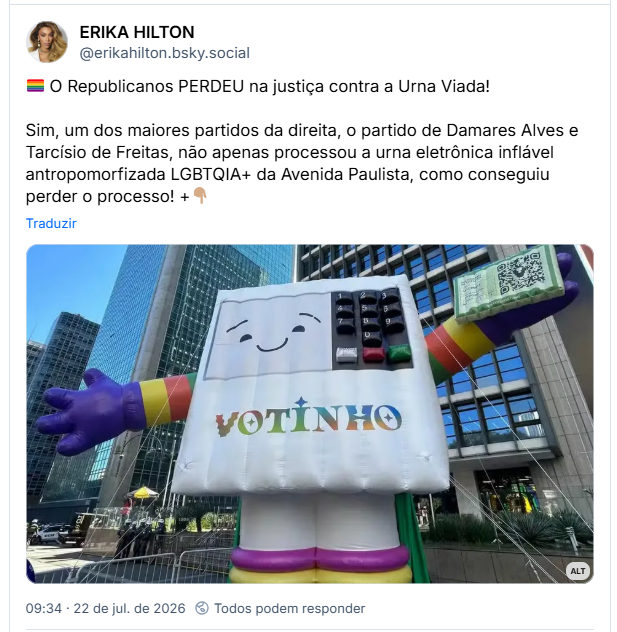 Post de ERIKA HILTON (@erikahilton.bsky.social): 🏳️‍🌈 O Republicanos PERDEU na justiça contra a Urna Viada! Sim, um dos maiores partidos da direita, o partido de Damares Alves e Tarcísio de Freitas, não apenas processou a urna eletrônica inflável antropomorfizada LGBTQIA+ da Avenida Paulista, como conseguiu perder o processo! +👇🏽
(Foto de um boneco inflável do mascote Votinho, uma urna eletrônica antropomorfizada, vestindo mangas e botas com as cores do arco-íris e segurando um título de eleitor em uma de suas mãos, erguido na Avenida Paulista.)