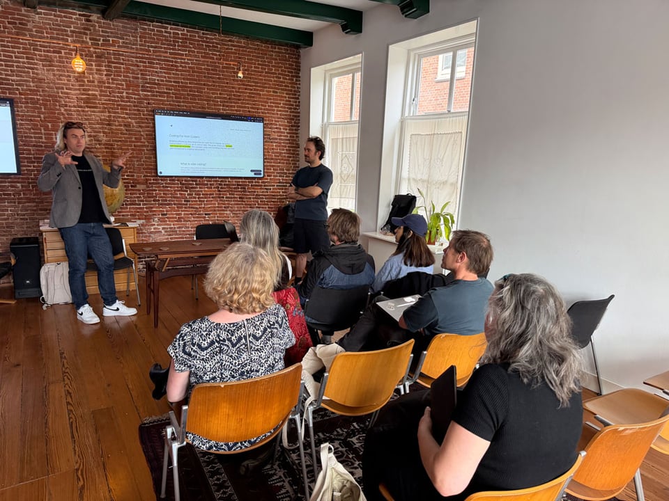 Two men present to an seated audience about the phenomenon of "vibe coding"