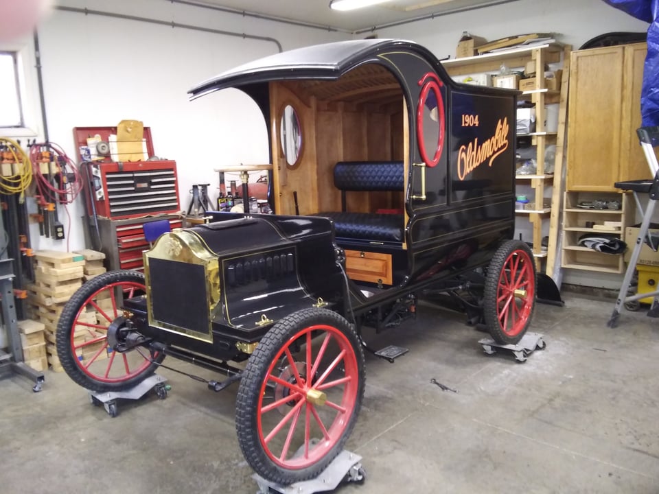 The nearly complete vehicle sits atop blocks with casters in the workshop