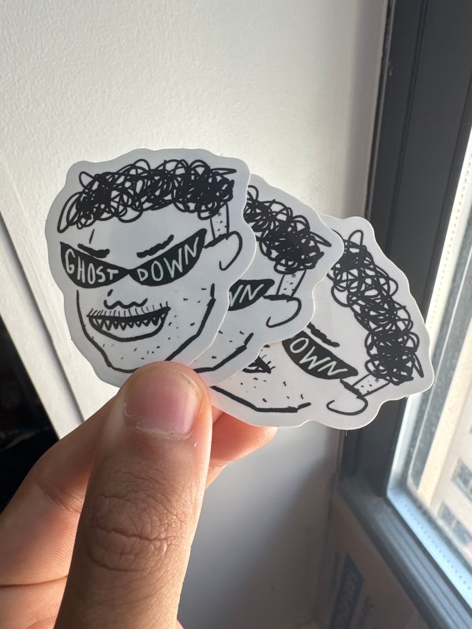 stickers of an evil cartoon version of my face with 'ghost down' across a pointy pair of shades.