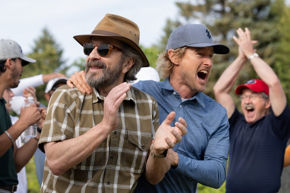 Marc Maron and Owen Wilson in a scene from "Stick," on a golf course and embracing in celebrating.