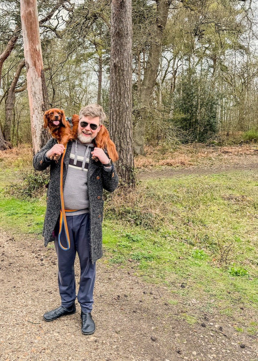 Man holds dog around his shoulders.