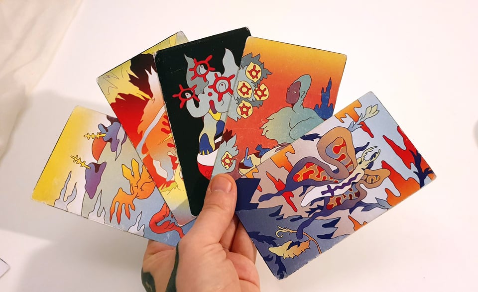 a hand holding five worn-out tarot cards