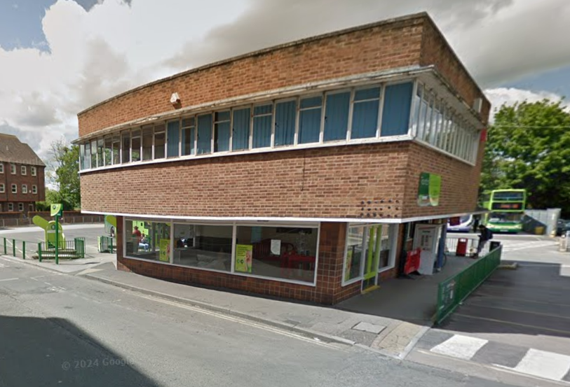 A google street view screen shot from about ten years ago, showing a 1950s or 1960s bus station. It's two storeys high and brick clad, with the first floor projecting around all the sides to provide shelter. The first floor has a ribbon window around three sides of it, very like an airport control tower. But for buses.
