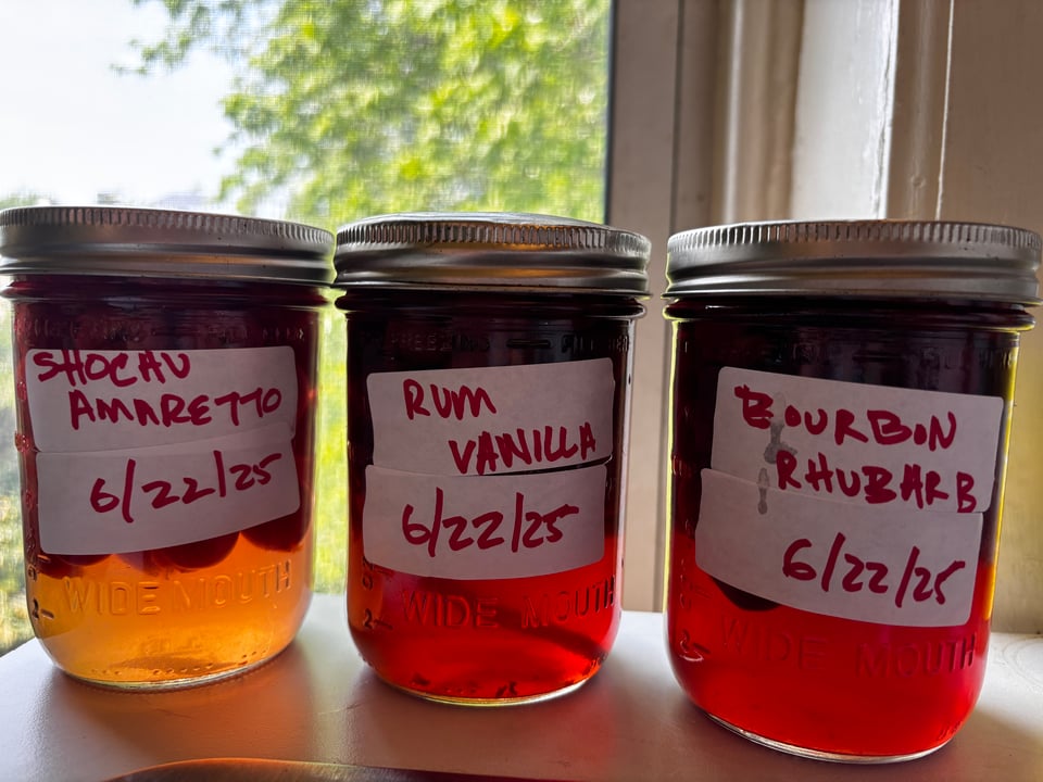 3 jars of preserved cherries, labeled schochu amaretto, rum vanilla, bourbon rhubarb, 6/22/25